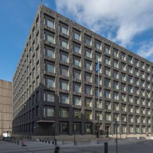A composite image of Erik Thedéen, governor of Sweden's Central Bank Riksbank next to a stock image of the Riksbank.