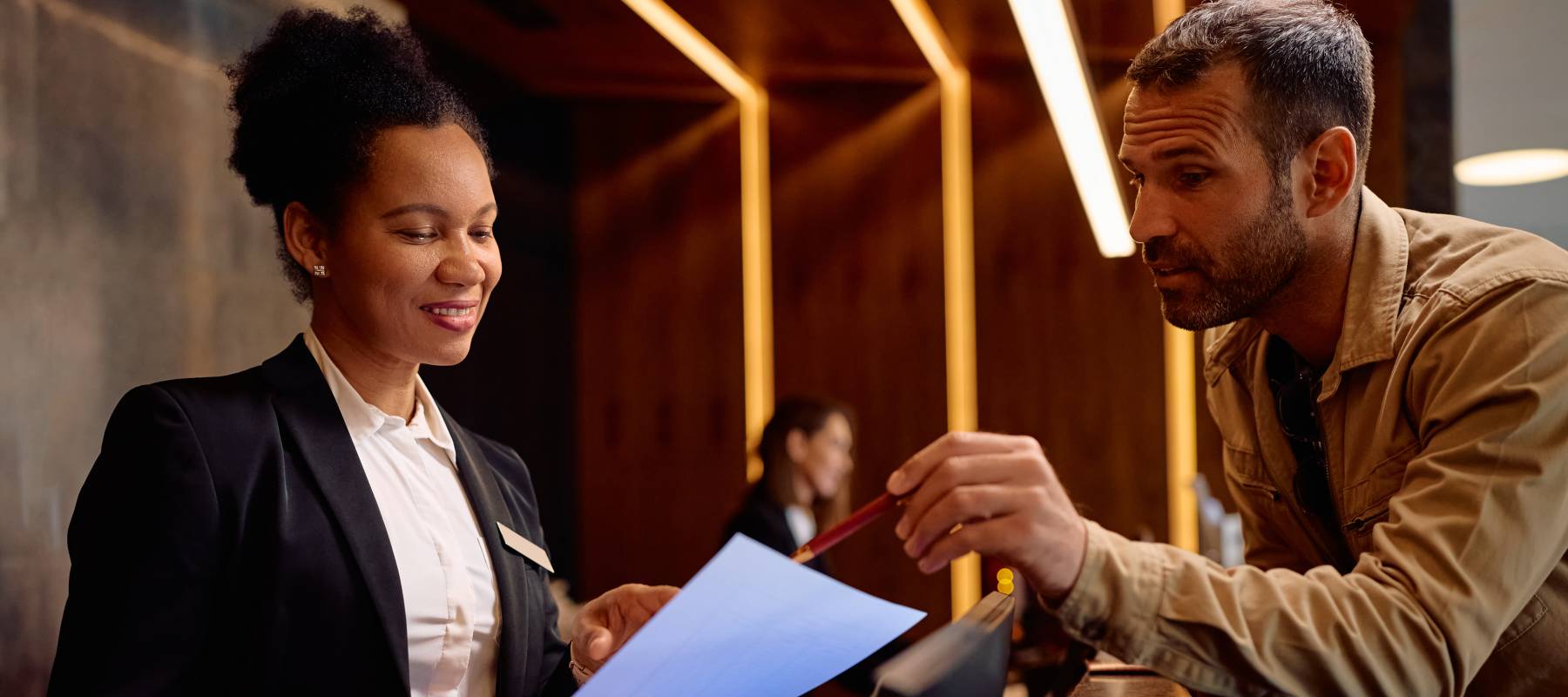 A man points to a bill at a hotel, one place where people are paying extra 'resort' and other fees.