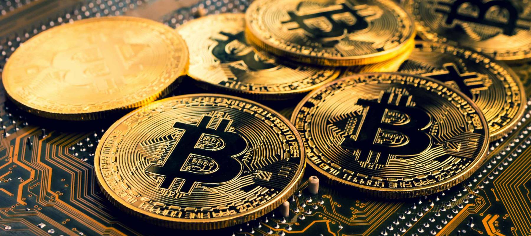 Golden coins with bitcoin symbol on a mainboard.