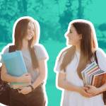 Two happy student girls walking and talking to each other on campus.