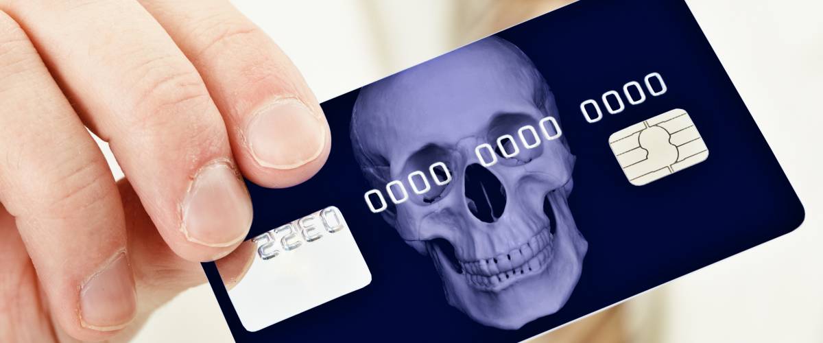 Hand holding a credit card with skull on it