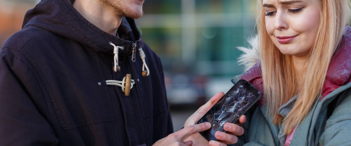 Man showing woman his cellphone with cracked screen