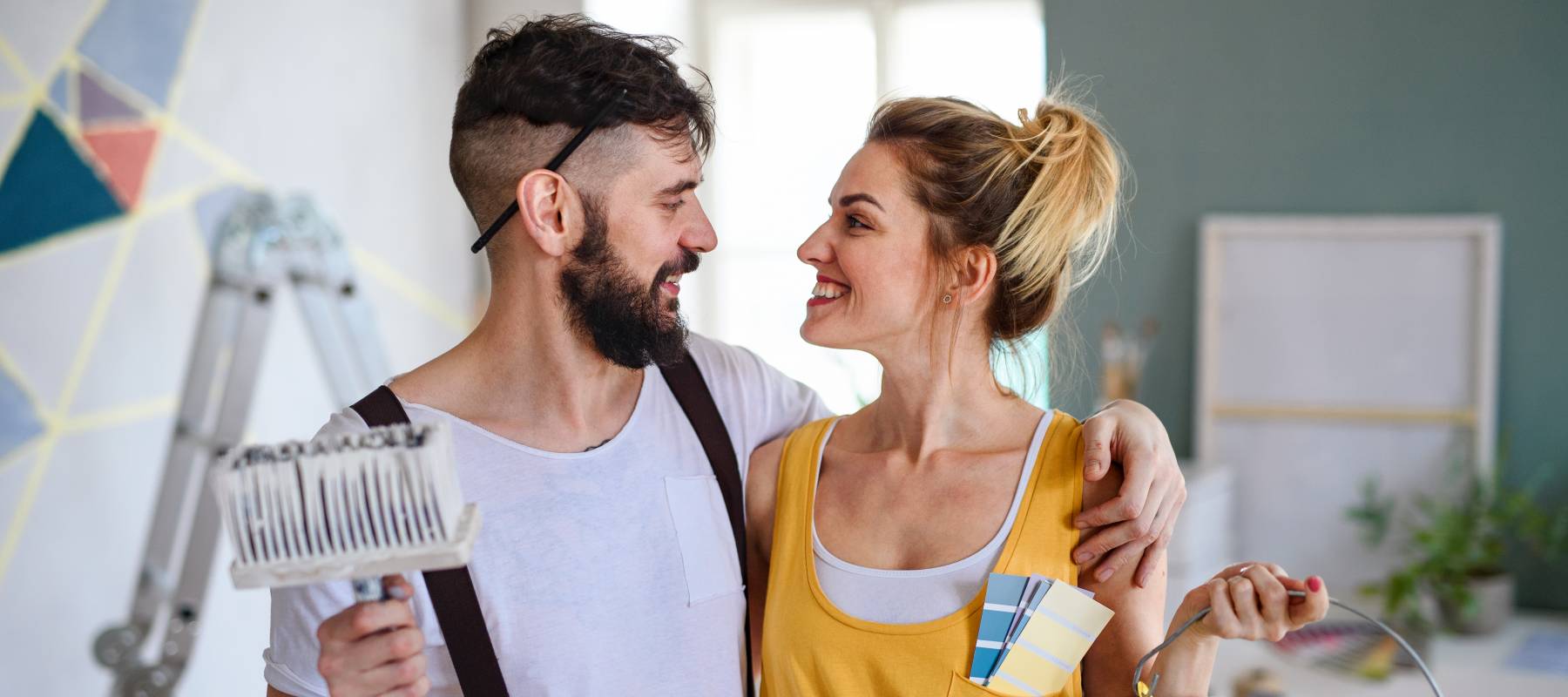 Couple having fun when painting wall indoors at home, relocation and diy concept.