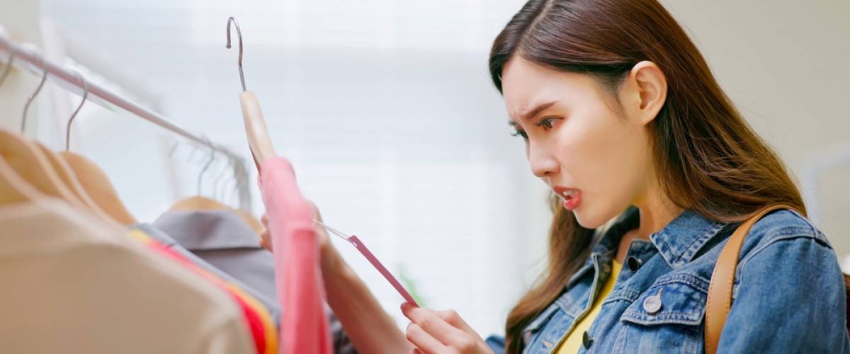Woman looking surprised at clothing price tag