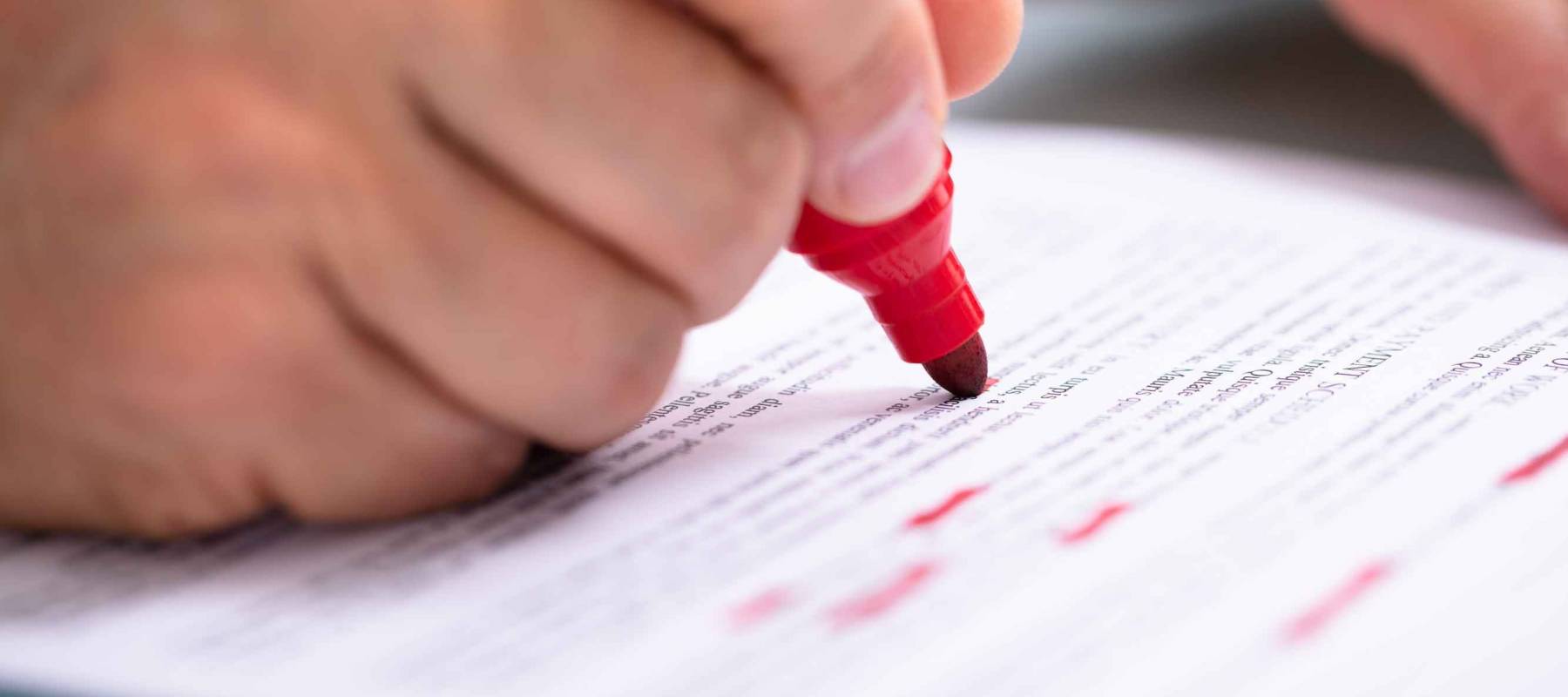 Close-up Of A Businessperson's Hand Marking Error With Red Marker