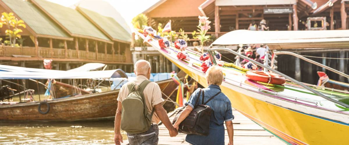 Happy senior couple walking holding hand at Koh Panyi muslim floating village - Active elderly and travel lifestyle concept with retired mature people at Phang Nga bay Thailand