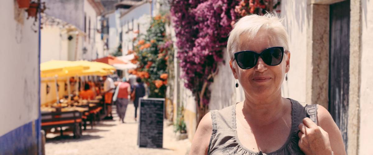 Senior woman tourist walking in a beautiful street full of flowers