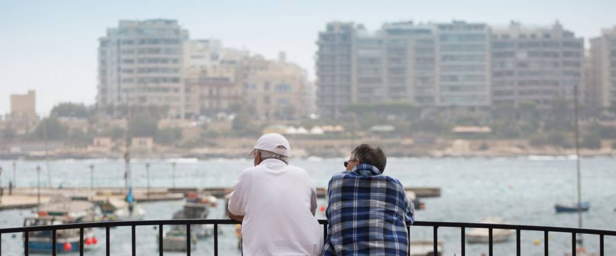 Two old mans at the pier watching city skyline and harbor