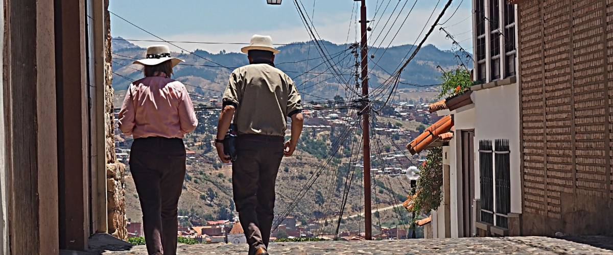 Man and woman, probably expats from Europe or North America, gingerly walk the streets of Sucre, Bolivia's capital.