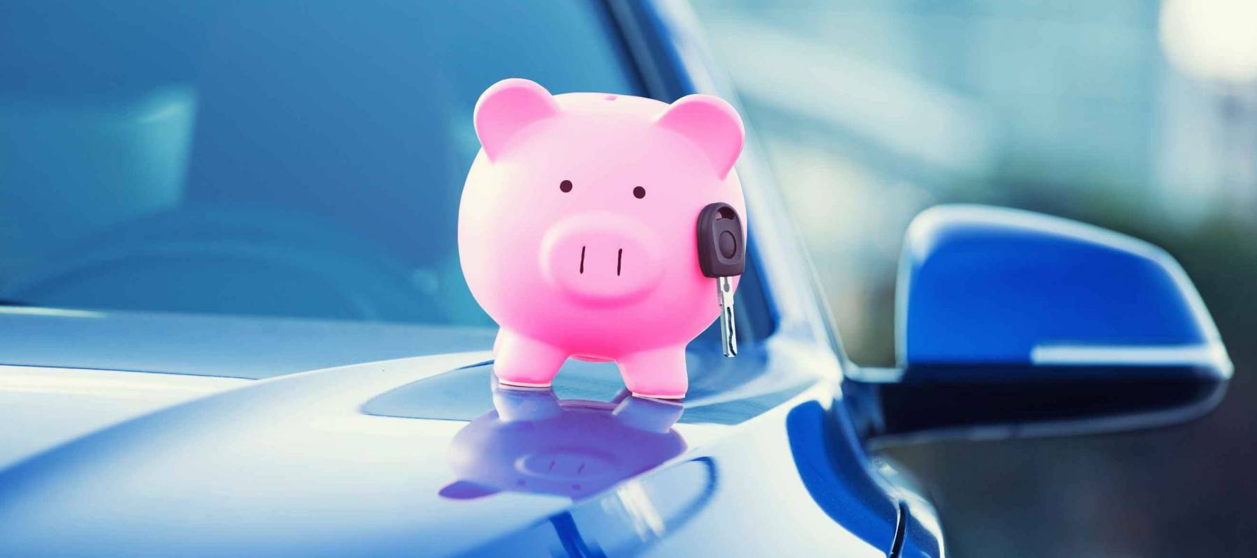 Closeup image new car with piggy bank, key on hood isolated outside corporate building.