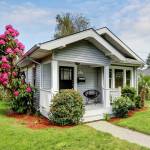 Cute craftsman home exterior with green grass and blooming tree. Northwest, USA