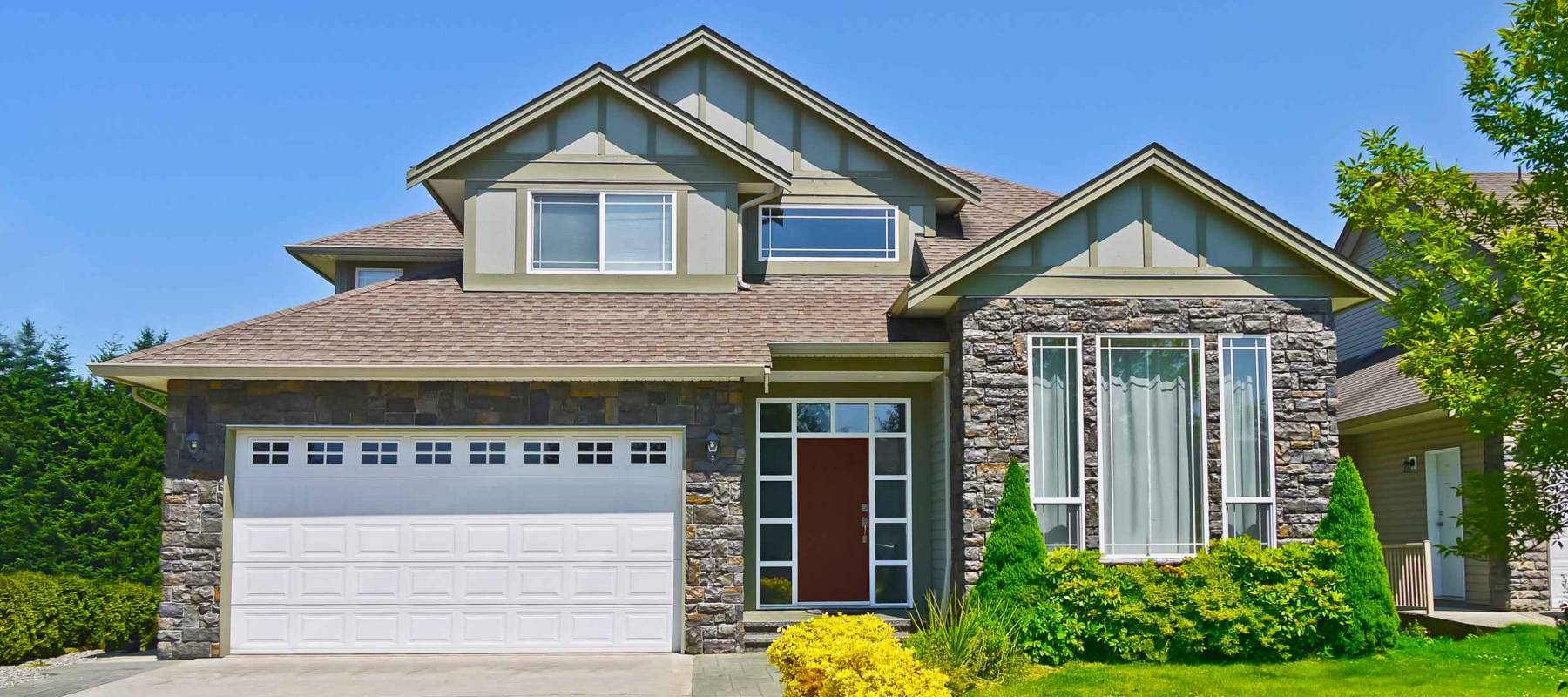 Luxury family house with concrete driveway to the garage on blue sky background