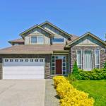 Luxury family house with concrete driveway to the garage on blue sky background