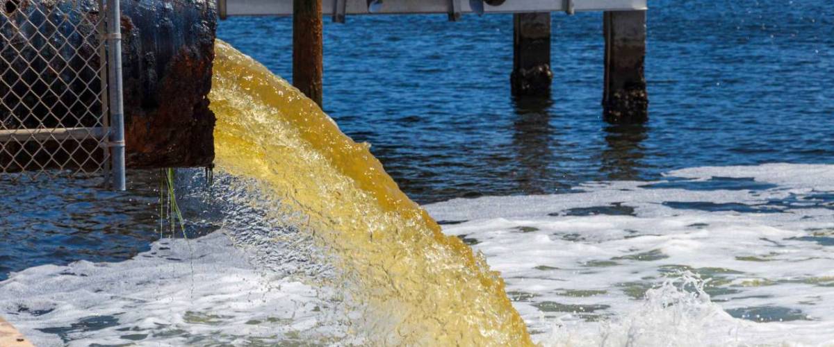 Raw untreated yellow water or sewage being pumped into a blue lake - Hollywood, Florida, USA