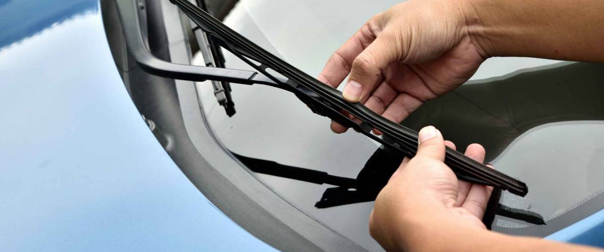 man hand picking up windscreen wiper or Mechanic check old wiper blade on customers sedan car.