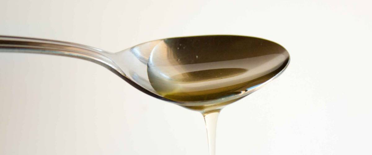 Agave nectar running off a metal spoon.