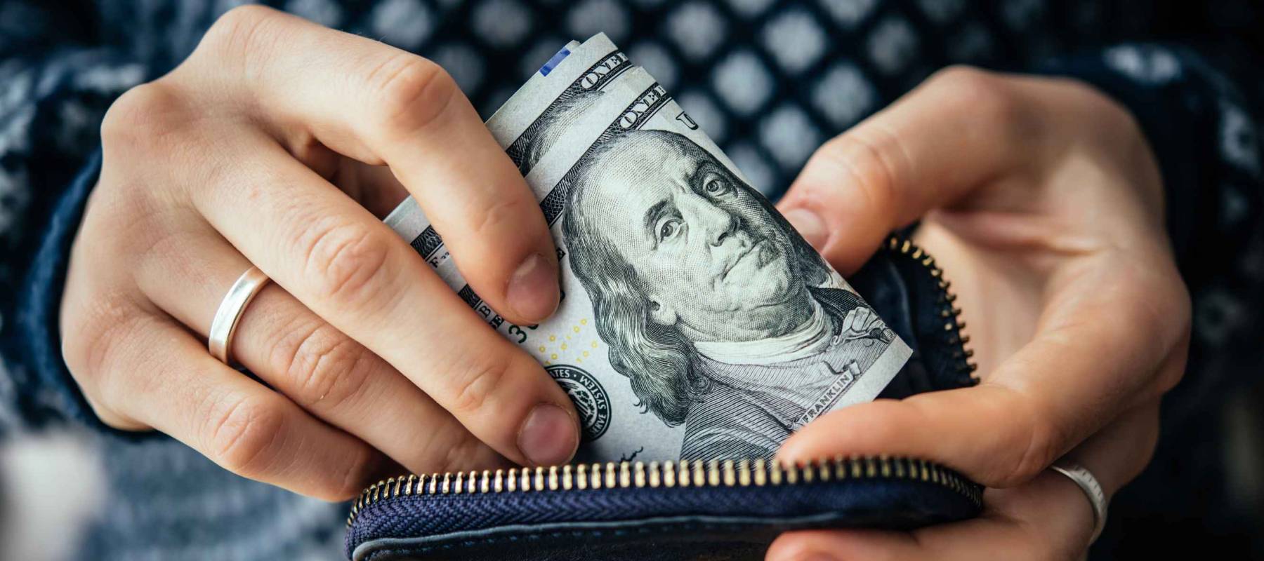 Hands holding us dollar bills and small money pouch