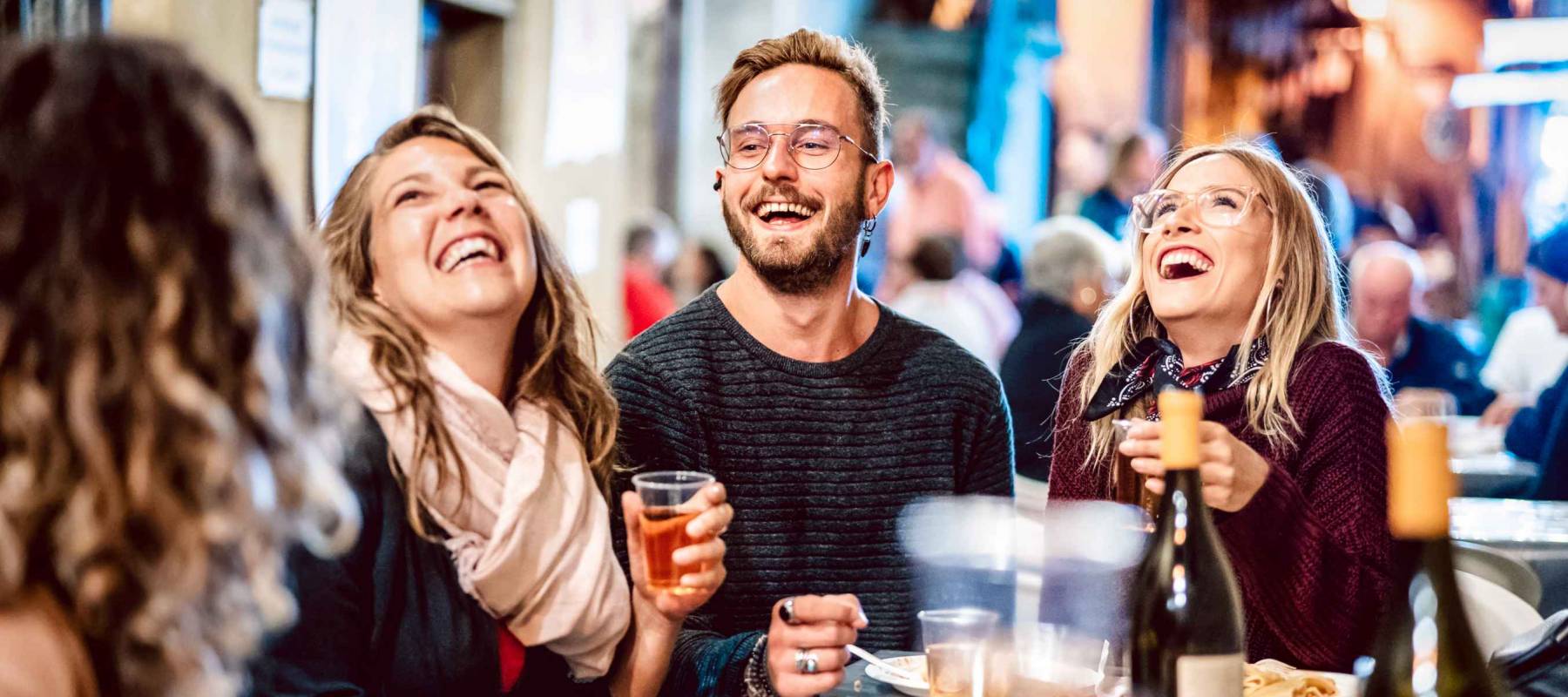 Happy friends having fun drinking white wine at street food festival