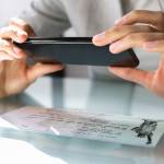 A person taking a cell phone picture of their stimulus check to deposit it