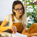 Millennial woman gardener remotely work from home on laptop, examines project documentation.