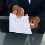 Close-up Photo Of Person's Hand Giving Cheque