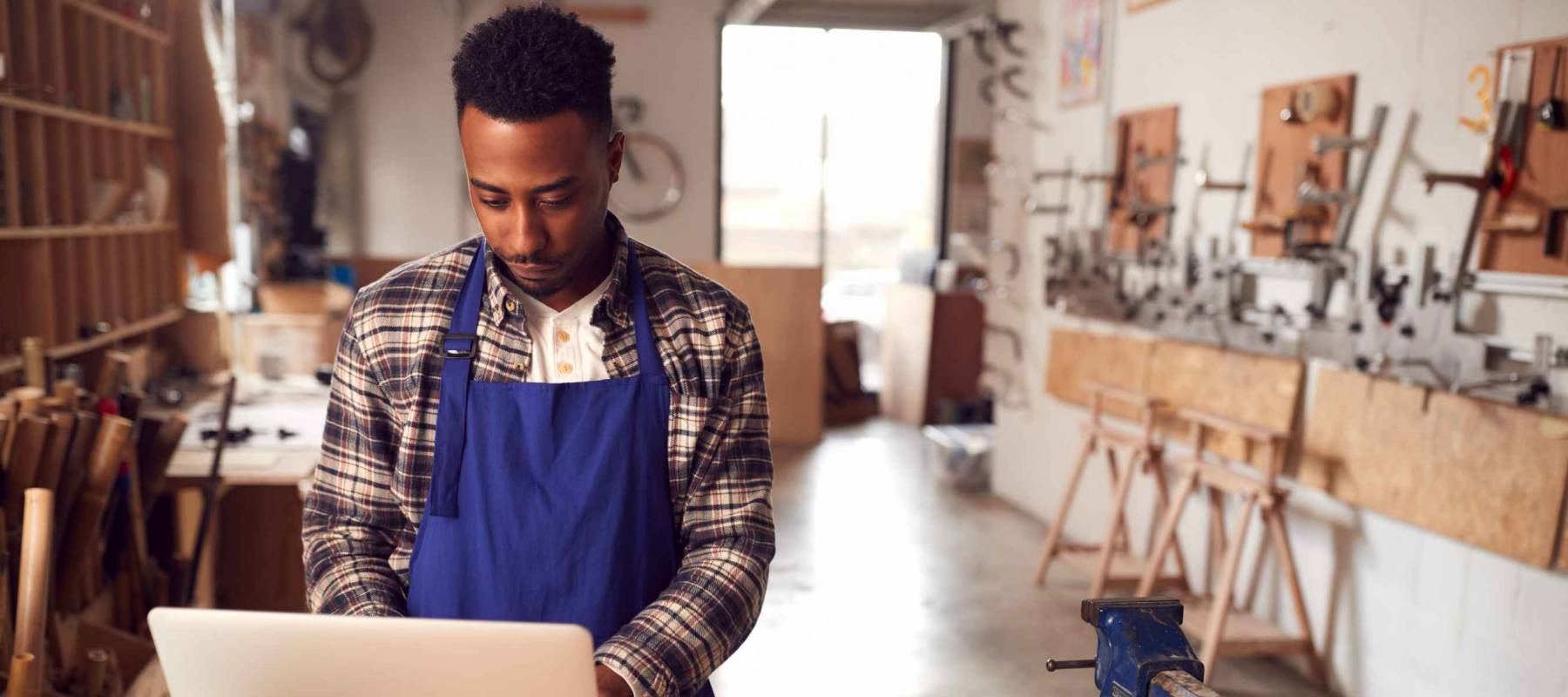 Male Craftsman In Carpentry Workshop On Laptop. hiring platforms for small business.