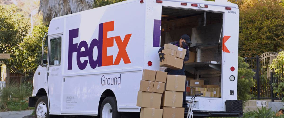 FedEx driver loading boxes into delivery truck day exterior