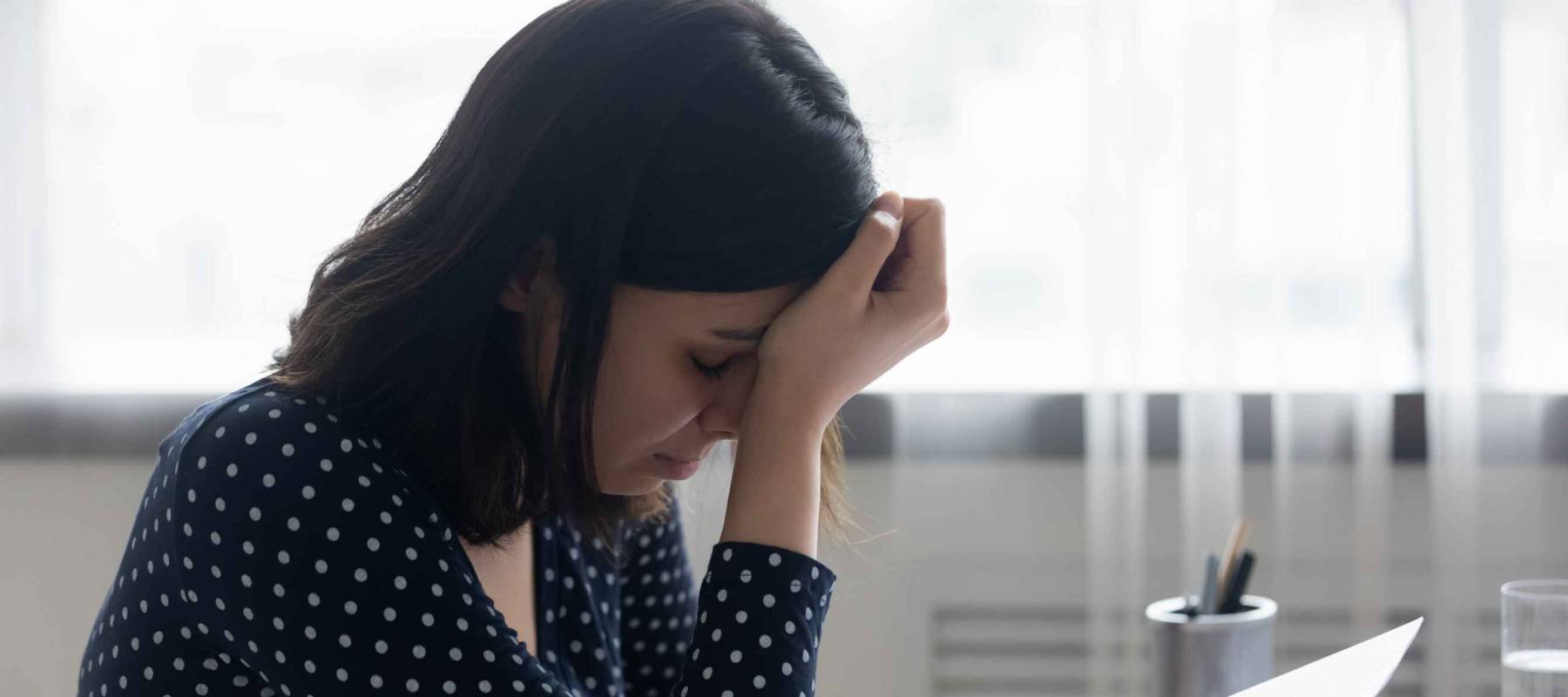 Stressed young asian ethnicity woman feeling desperate about getting paper eviction notification.