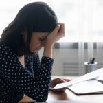 Stressed young asian ethnicity woman feeling desperate about getting paper eviction notification.