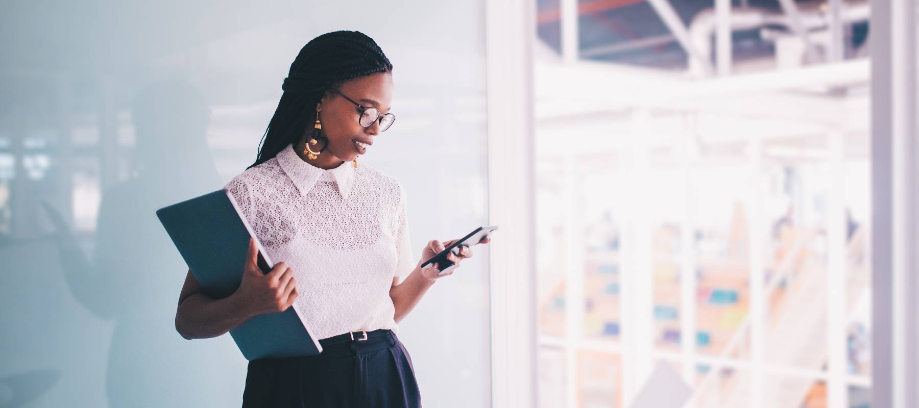 African American woman holding clipboard, looking at job posting website on cell phone