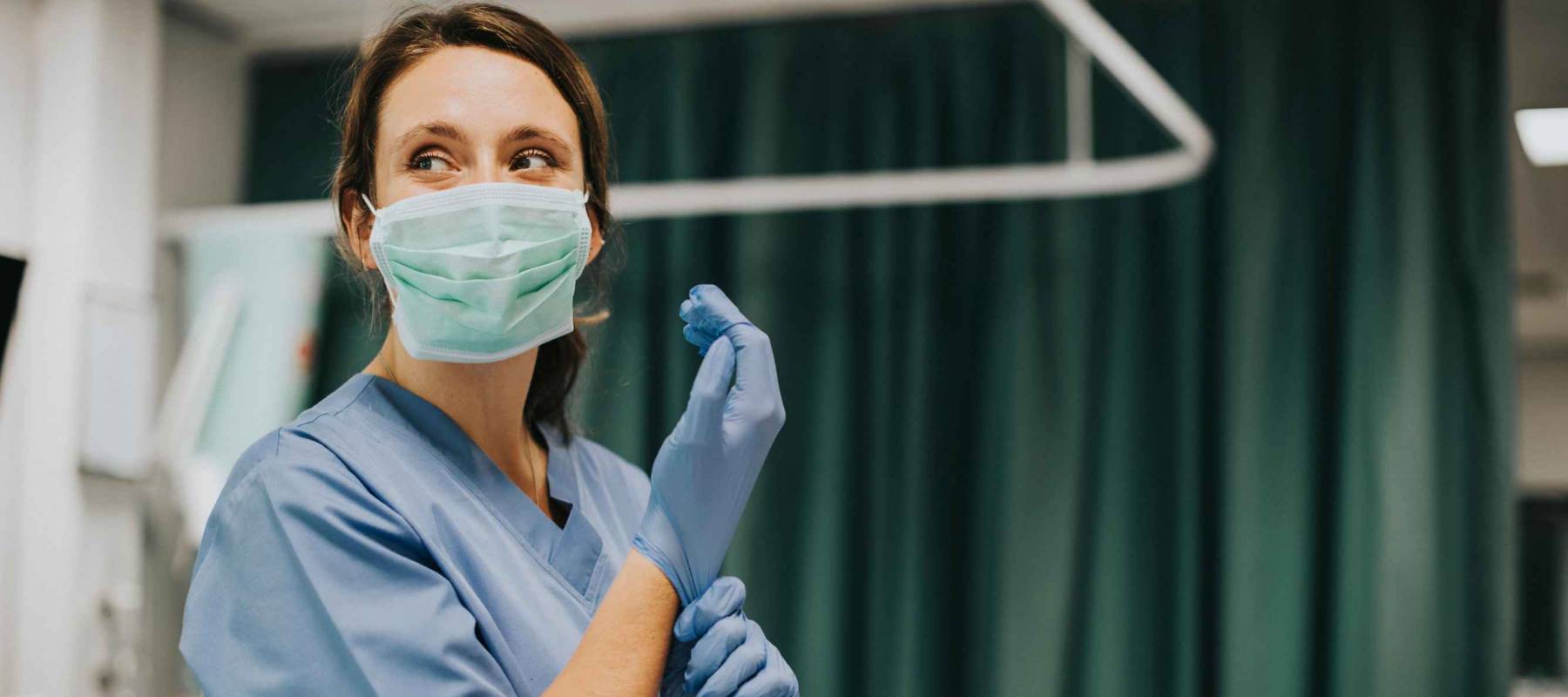 Female nurse with a mask putting on gloves