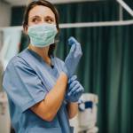Female nurse with a mask putting on gloves