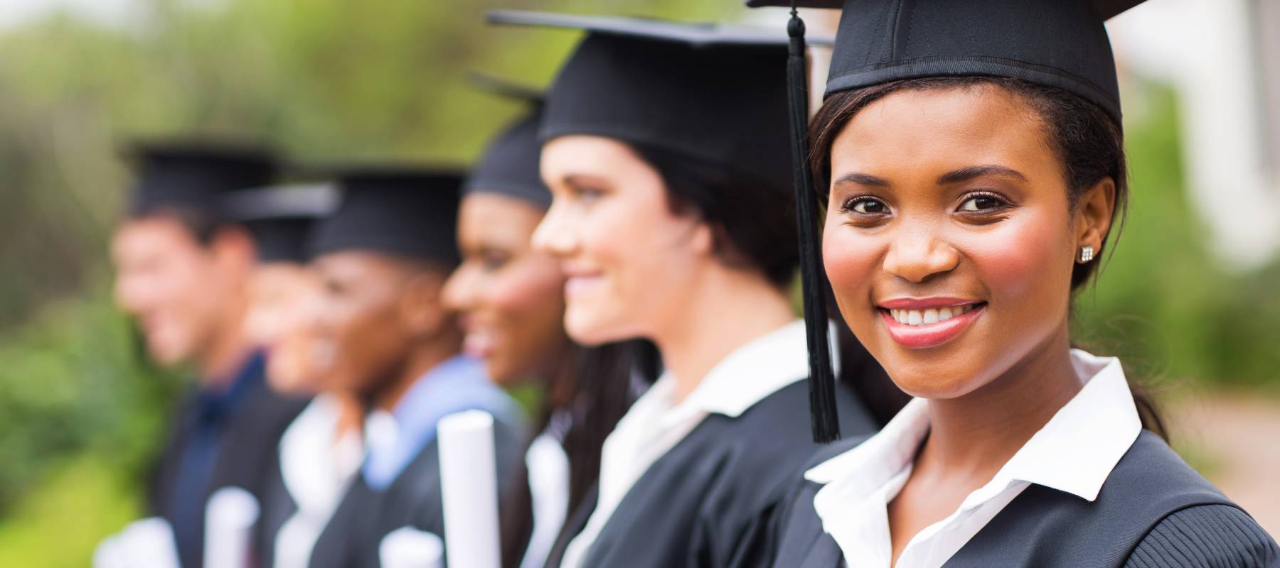 pretty african female college graduate at graduation with classmates