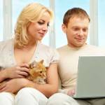 A young couple sitting on sofa and looking at laptop screen