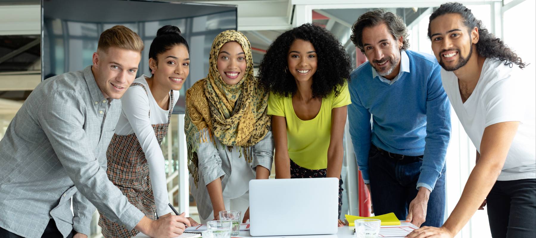 Front view of diverse business people looking at camera while working together at conference room in a modern office