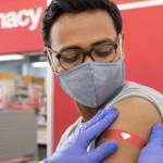 Pharmacist applying a band aid after flu shot