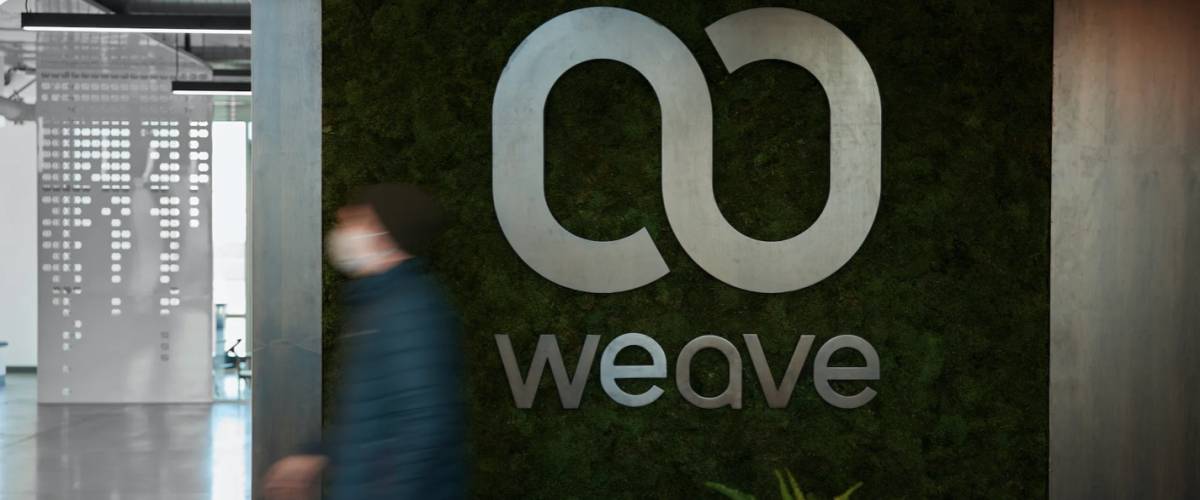 The logo for Weave Communications on the wall inside an office building