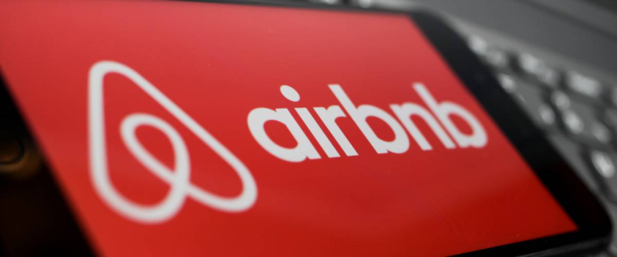 Close up of isolated mobile phone with red airbnb logo lettering on computer keyboard