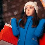 A woman with many holiday shopping bags and her eyes wide takes a deep breath from feeling overwhelmed