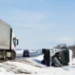 Truck and car crash on a snowy interstate highway.