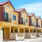 Row of colorful, red, yellow, blue, white, green painted residential townhouses, homes, houses with brick patio gardens in summer
