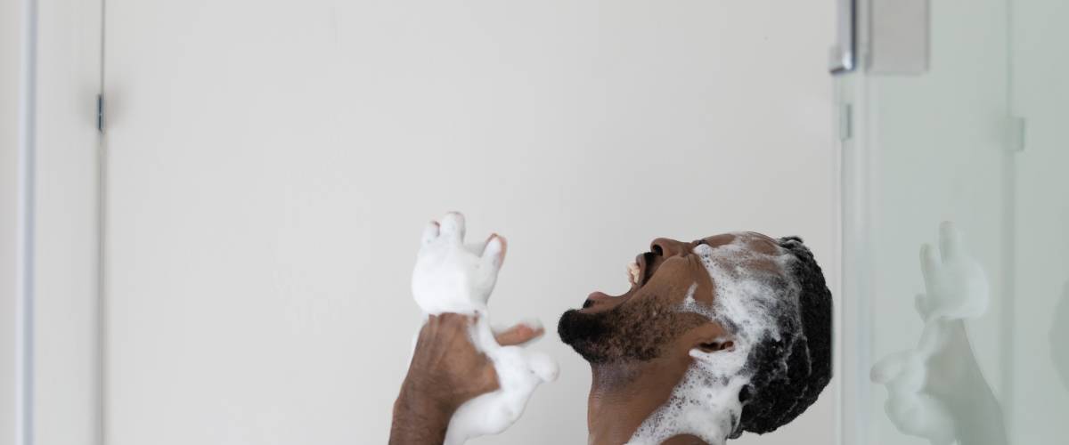 Man with soap over his eyes in a shower that's suddenly turned off