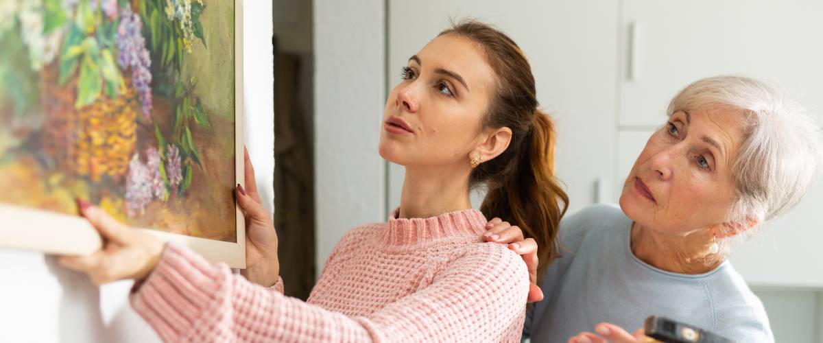 two women hanging a photo on a wall