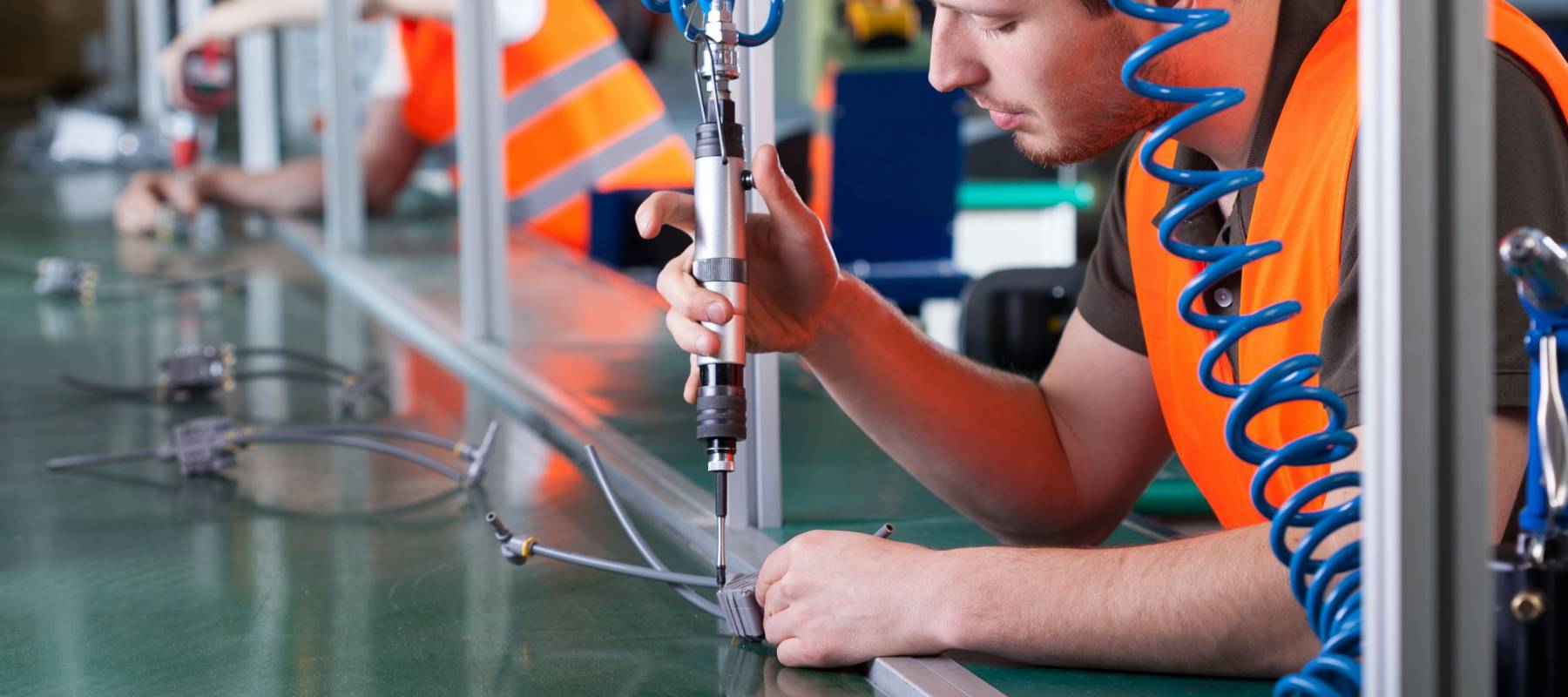 Men during precision work on production line, horizontal