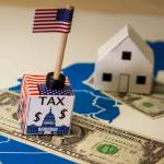 Family houses with dollar bills and central goverment tax over a US map.USA finance and economy concept related to the Tax Cuts and Jobs Act. approved by the Senate in December