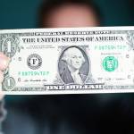 A man holds a U.S. 1 one dollar.