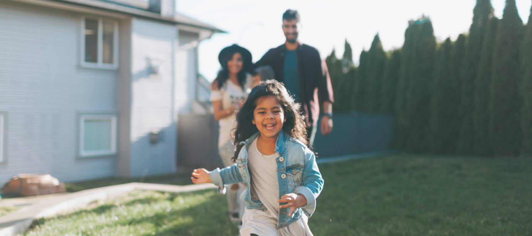 Parents and daughter playing in yard outside their house