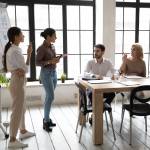 Indian and caucasian businesswomen flip charts presentation new project in boardroom at company meeting.