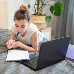 Teen girl uses laptop at home.
