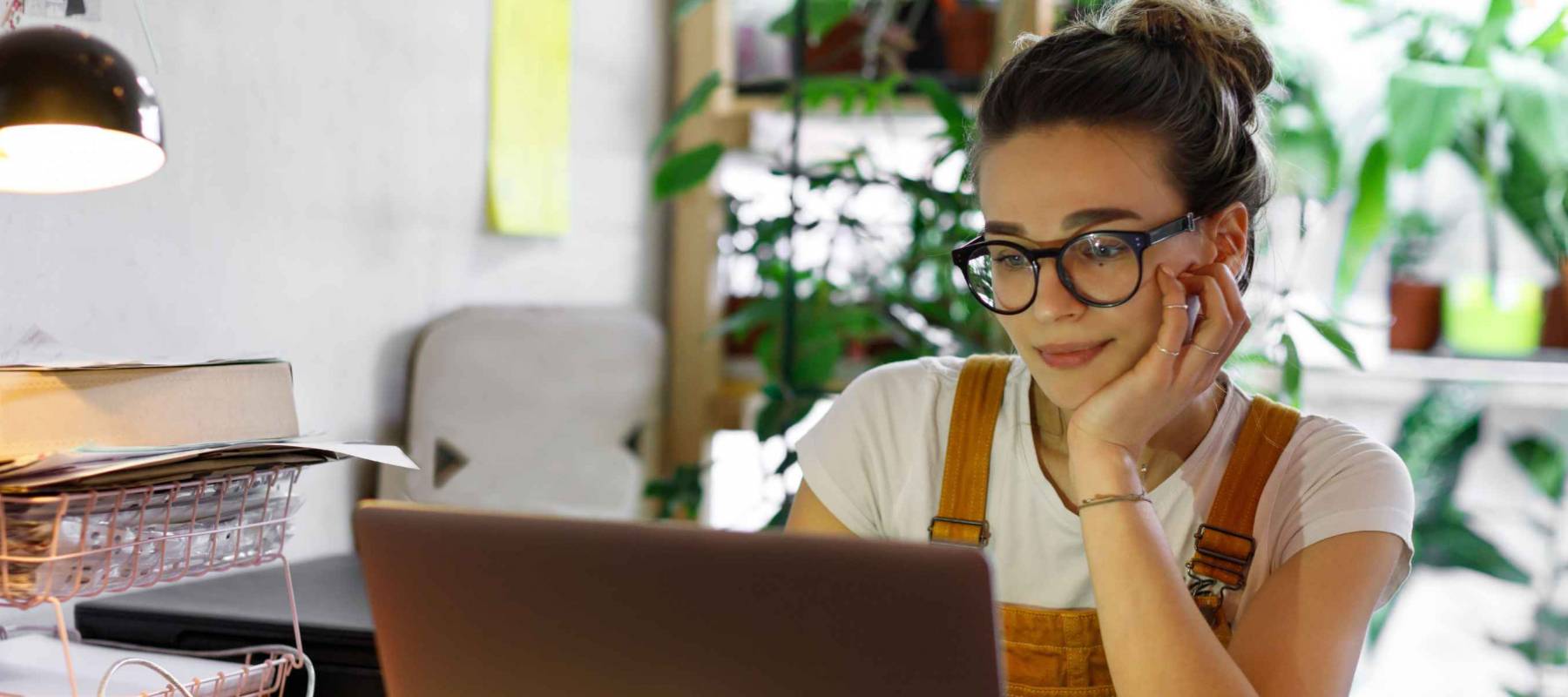 Young female gardener in glasses using laptop for remote work,